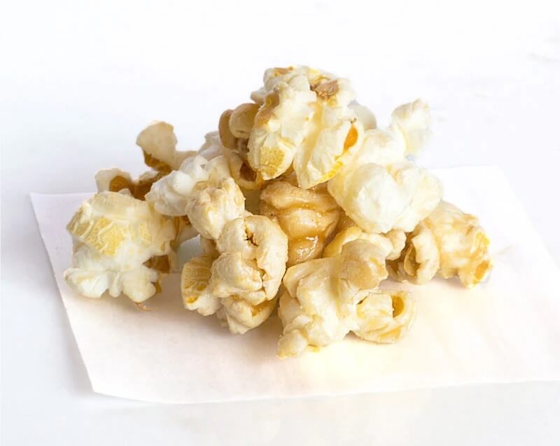 A small pile of caramel popcorn sits enticingly on a white piece of paper.