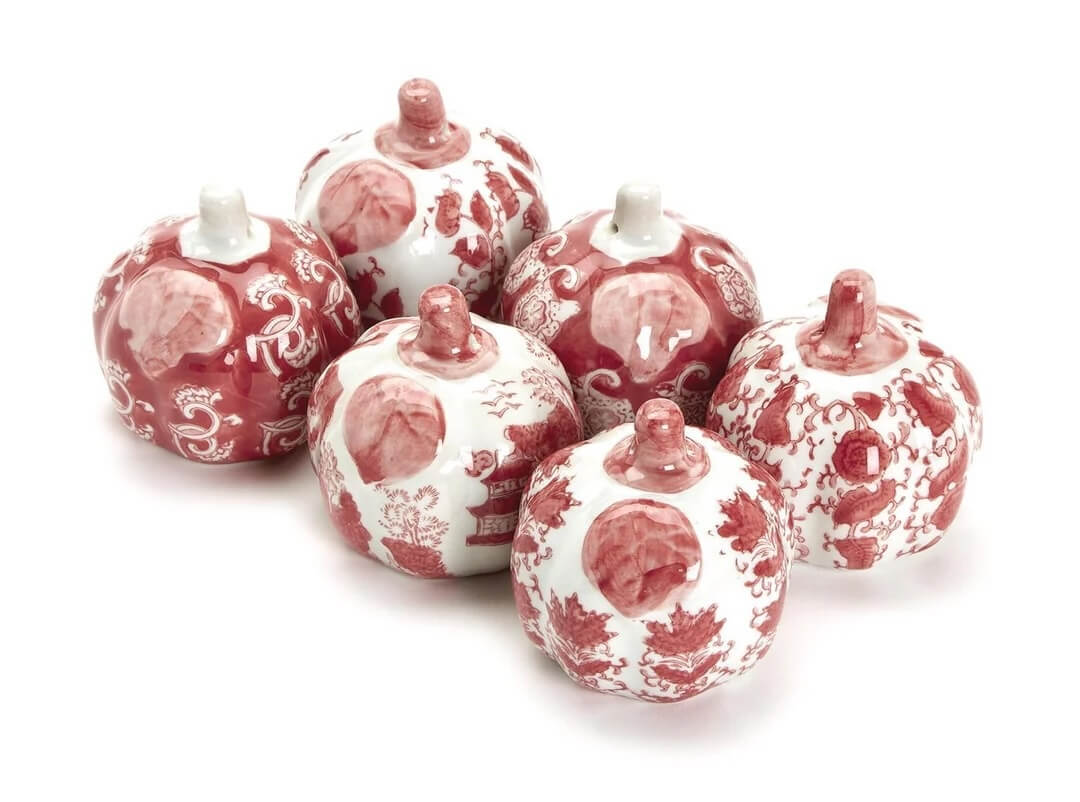 Six ceramic pumpkins with white backgrounds and red intricate designs are arranged together, capturing the essence of October.