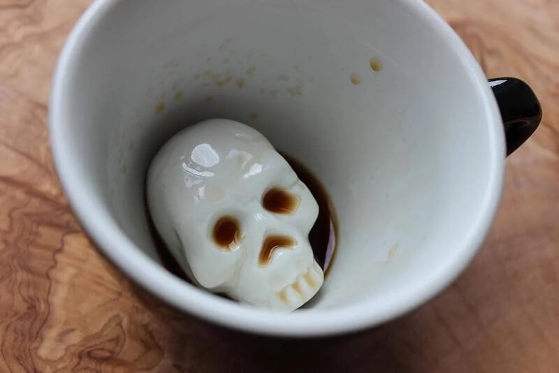 A white coffee mug with the remains of dark liquid at the bottom, revealing a ceramic skull submerged in the liquid—one of my most intriguing October FINDS in Nashville.