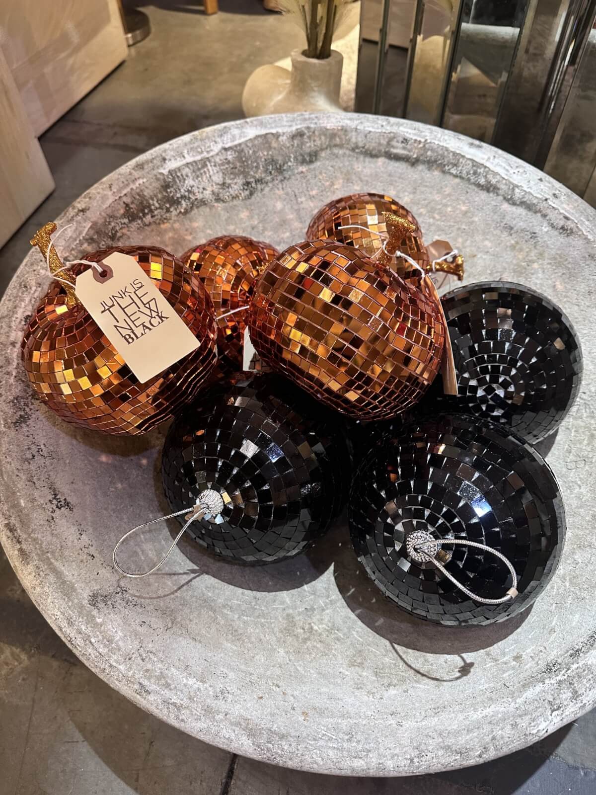 A bowl featuring Nashville FINDS, showcasing shiny, disco ball-style ornaments in copper and black hues.