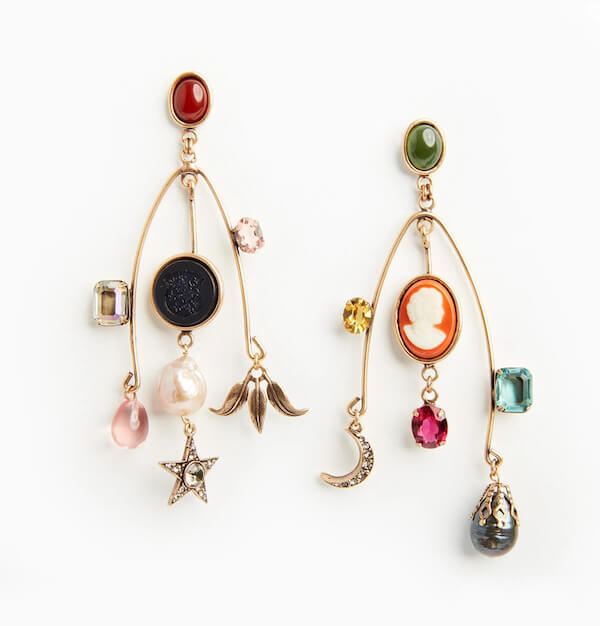 Asymmetrical gold earrings with various FINDS, including cameos, gemstones, a pearl, star, crescent moon, and fruit. Each earring features a unique combination of decorative elements.