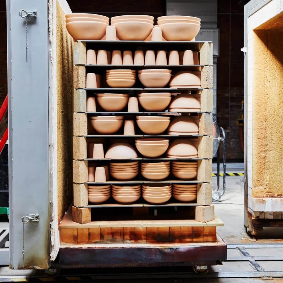 A kiln filled with stacked, unglazed ceramic bowls and cups from East Fork Pottery, ready for firing in a pottery workshop.