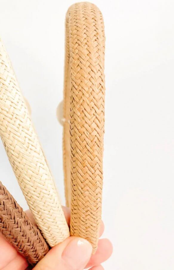 A hand holds three woven rattan handles in brown, beige, and tan colors—stylish FINDS against a plain white background.
