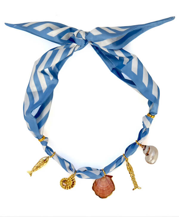 A blue and white striped scarf tied in a knot, adorned with gold and seashell charms shaped like a fish, a shell, a seahorse, and a spiral shell—perfect for showcasing your coastal FINDS.