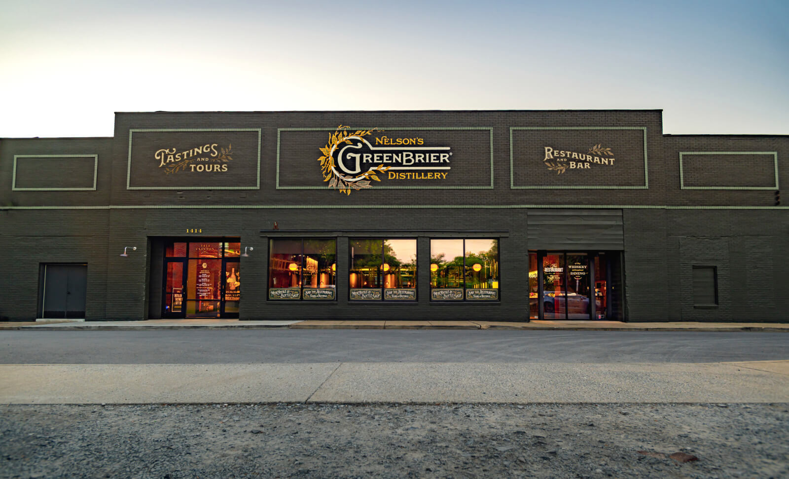 Exterior of Nelson's Greenbrier Distillery, where history comes alive through entrances for tastings, tours, and a restaurant and bar, all set against large windows and an industrial-style brick facade.