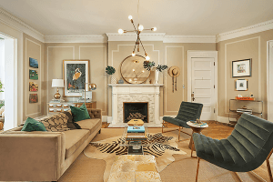 Unit D on South 4th Street in Louisville boasts a contemporary living room featuring a beige sofa, green chairs, a marble fireplace, and a zebra-pattern rug. Modern lighting hangs overhead, and the walls display various artworks and a round mirror.