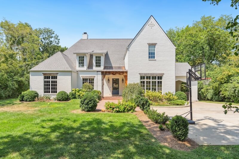 A two-story white brick house with a gable roof, manicured lawn, and a basketball hoop in the driveway located at 4221 Lindawood Dr, Nashville TN.