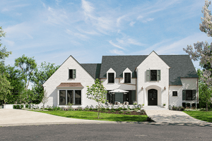 A large white brick house with a dark gray roof, multiple windows, and a curved driveway surrounded by trees and a well-manicured lawn in the serene neighborhood of Poplar Hill Bluff, Louisville KY.