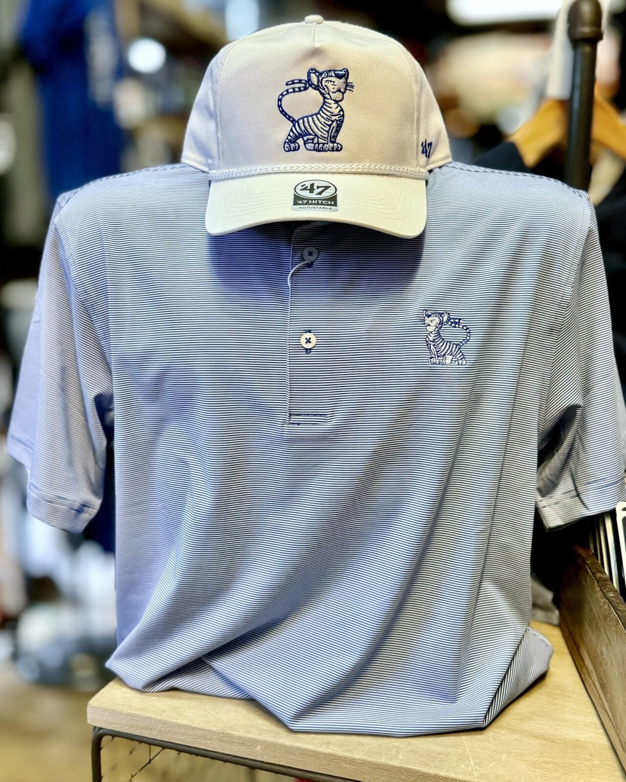 A light blue polo shirt and matching cap, both featuring an embroidered logo of a cartoon tiger