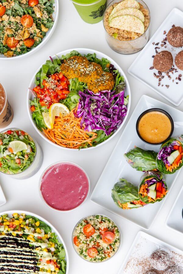 9 New Nashville Restaurants to Try This Month - 10 A variety of colorful and healthy dishes, including salads, vegetable wraps, smoothie bowls, and beverages, arranged on a white table.