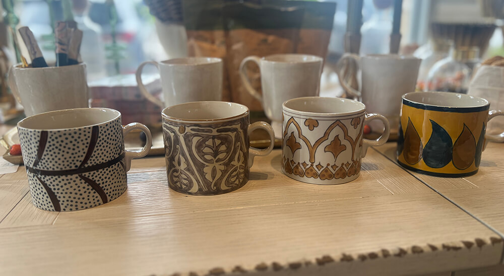 A set of five ceramic mugs with various intricate patterns and designs displayed on a wooden surface. 