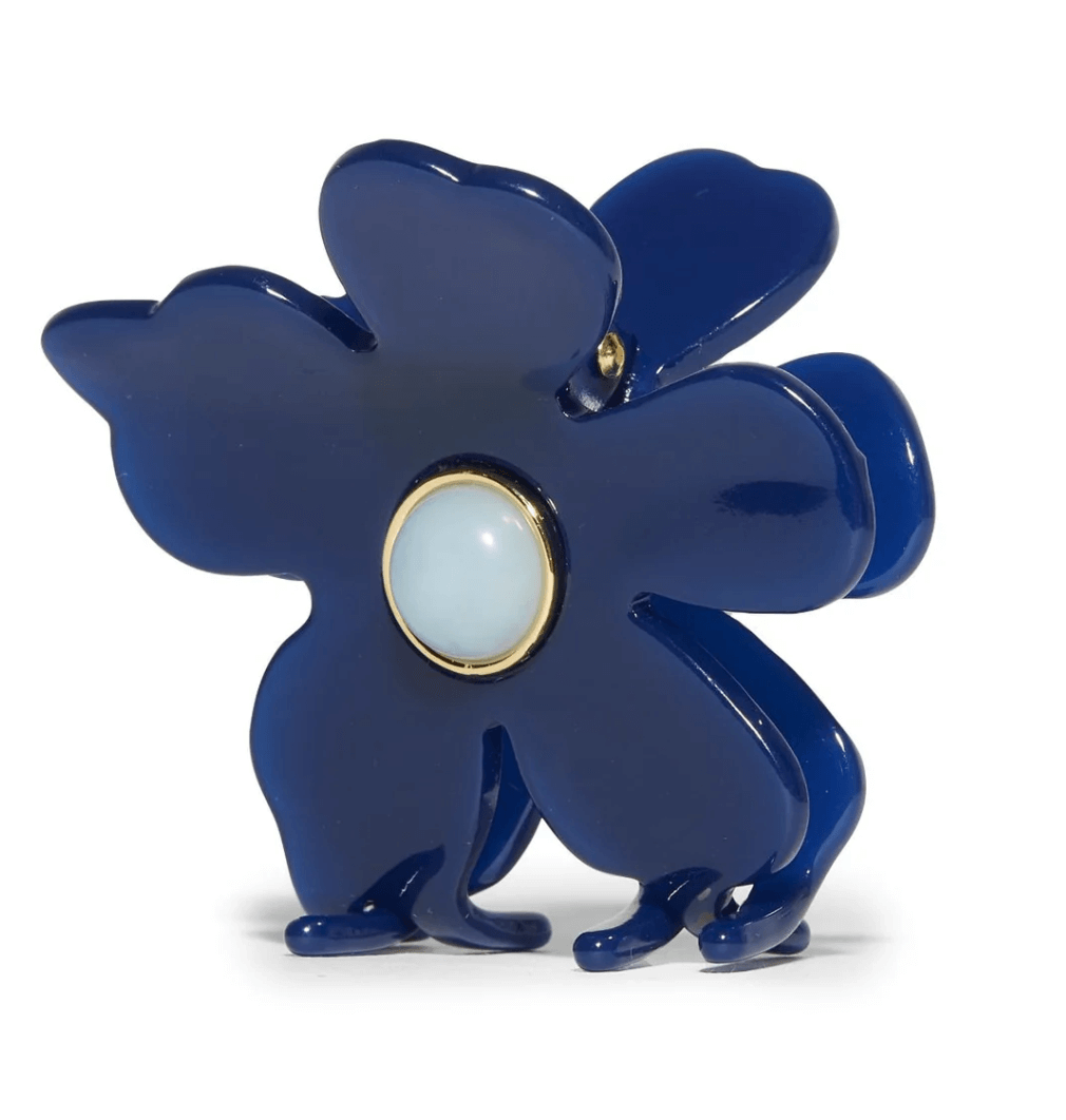 A dark blue, flower-shaped plastic hair clip with a central round, light-colored gem-like detail.
