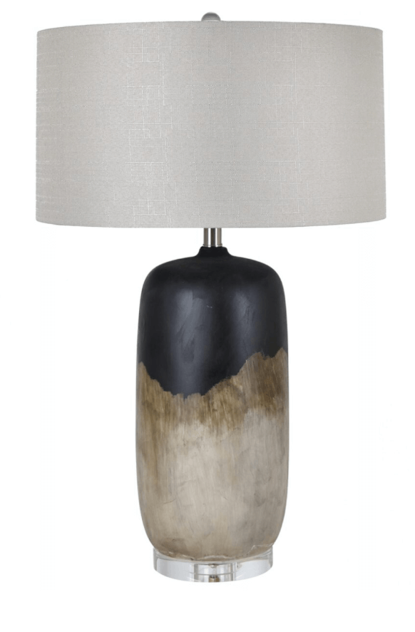 Table lamp features a dual-toned cylindrical base in black and sandy beige, topped with a neutral-colored fabric lampshade.