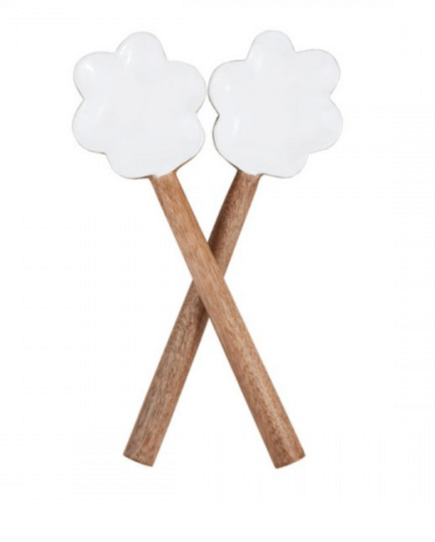 Two wooden utensils with white, flower-shaped heads are elegantly crossed together against a plain background. 