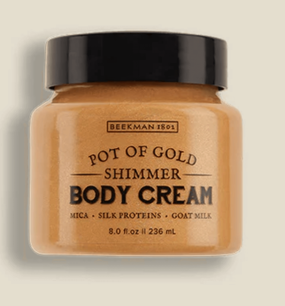 A jar of Beekman 1802 Pot of Gold Shimmer Body Cream. The label indicates it contains mica, silk proteins, and goat milk, with 8.0 fl. oz. (236 mL).