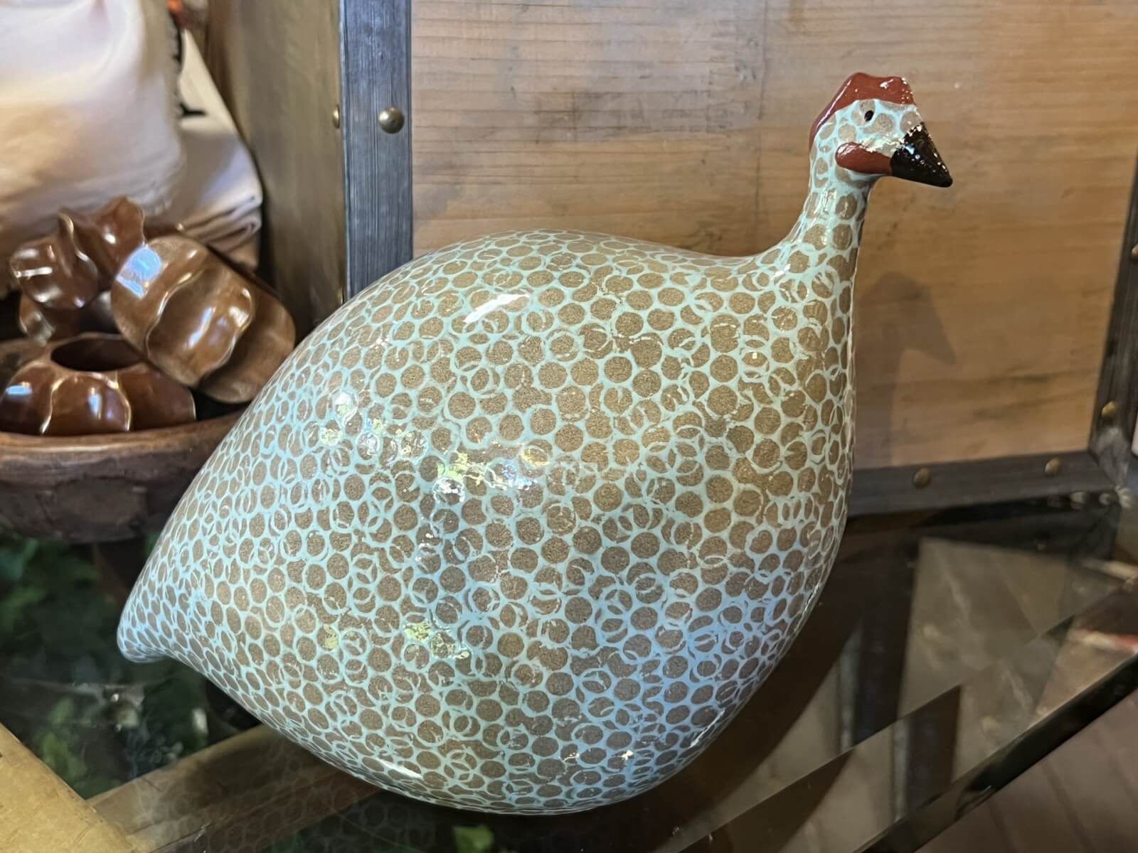 A ceramic figurine of a bird with a speckled pattern and a small beak displayed gracefully on a glass surface.