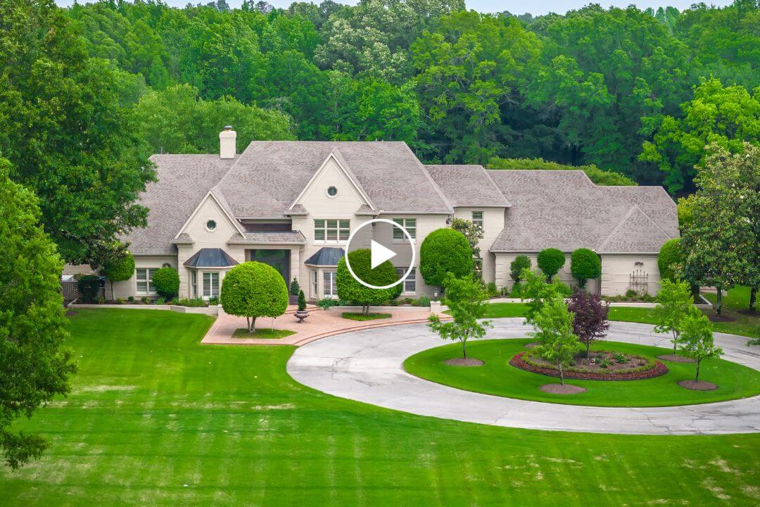 This large suburban house, located on Shea Rd. in Collierville, TN, boasts a gray roof framed by lush greenery and trees. It features a circular driveway and a well-manicured lawn, providing an inviting and serene atmosphere.