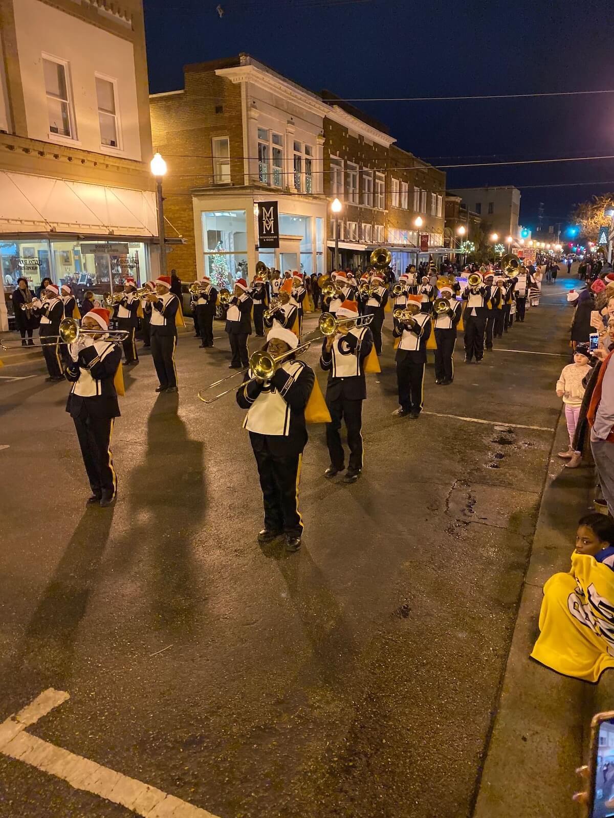 A marching band lights up the streets of one of Mississippi's best towns as they perform in a nighttime holiday parade, cheered on by delighted spectators lining the sidewalks.