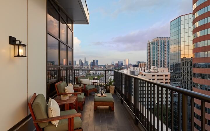 Experience a Nashville sunset from your rooftop balcony at Luxe Hotels. Enjoy the plush chairs and table with the city skyline as your perfect backdrop, nestled in vibrant Midtown.