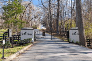 The gated entrance to River Glades community on River Glades Drive in Prospect, KY, is surrounded by trees with a paved road inviting you inside.