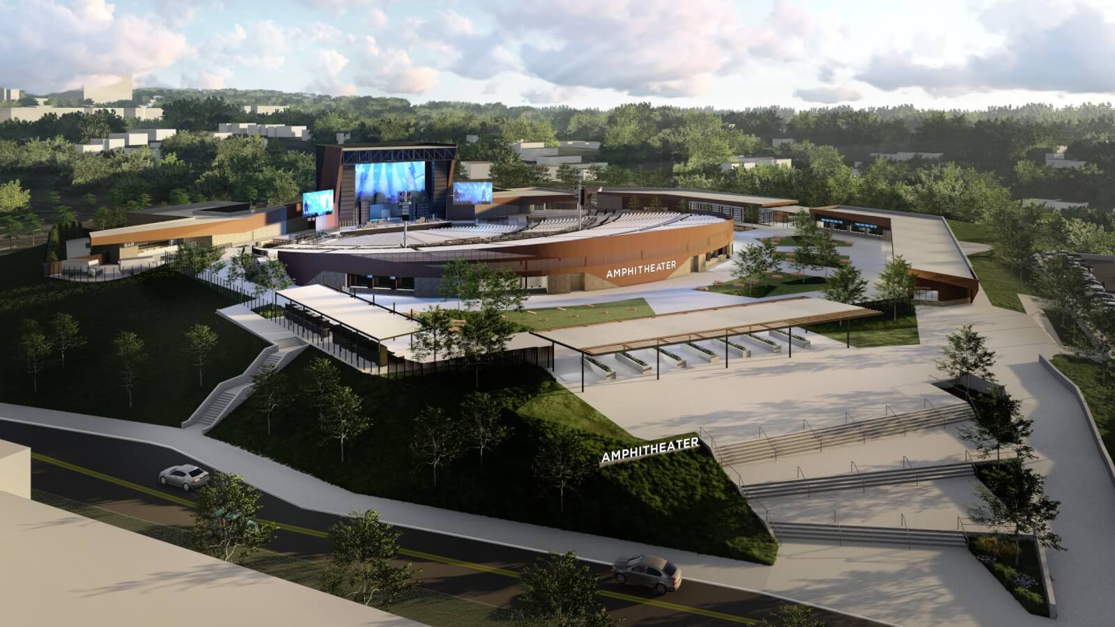 Aerial view of the Coca-Cola Amphitheater nestled in lush greenery. It features seating areas and pathways, with large screens displaying vibrant images.