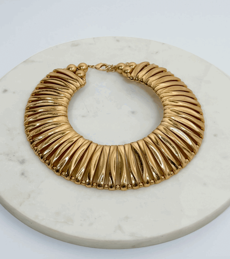 17 Birmingham FINDS for the New Year - 8 Gold statement necklace with a ribbed, fan-like design, featured as one of Birmingham FINDS January highlights, displayed on a round white marble surface.
