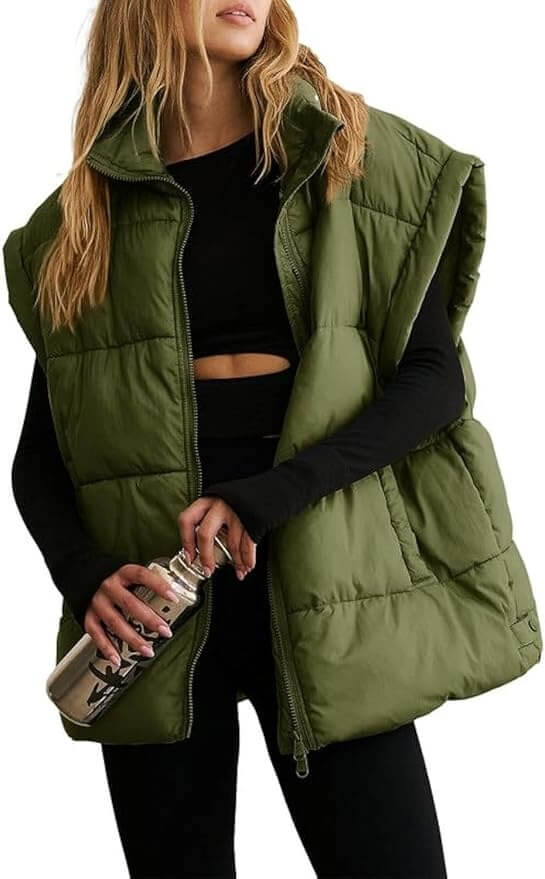 Person wearing a green puffer vest and black outfit holds a silver water bottle.