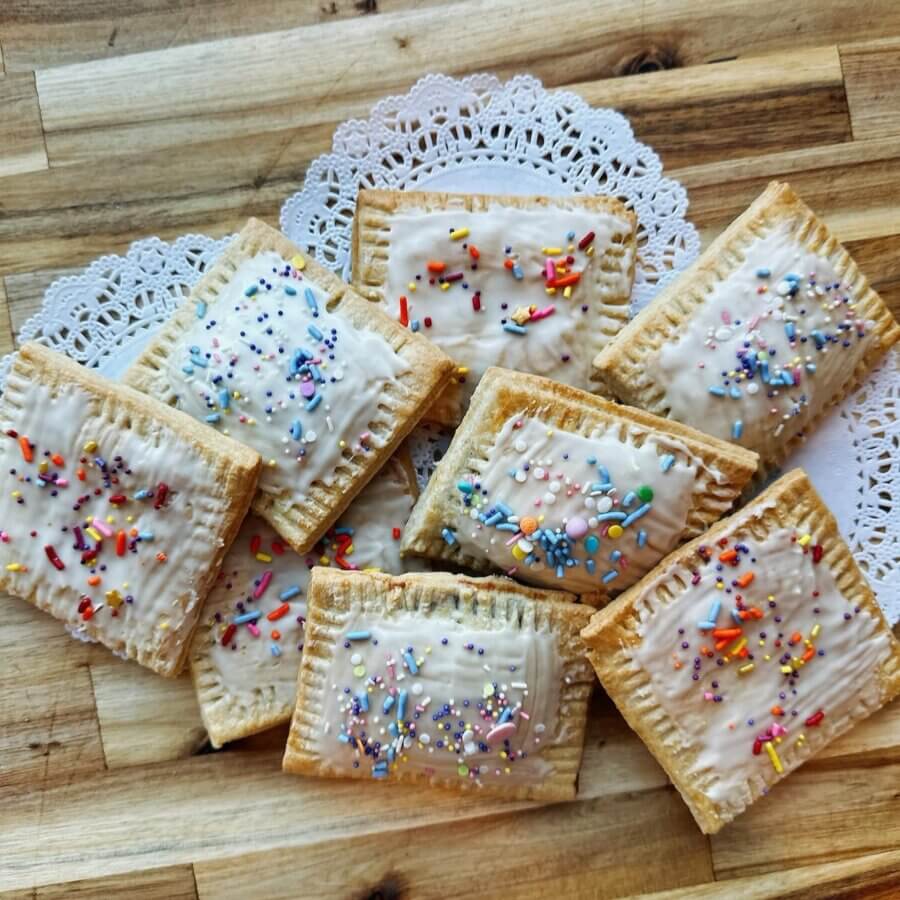 30+ Memphis Adult Education Classes to Enrich Your Life! - 3 Eight rectangular pastries with white icing and colorful sprinkles are arranged on a lace doily atop a wooden surfaceβperfect for sharing at your next Memphis adult education classes gathering.