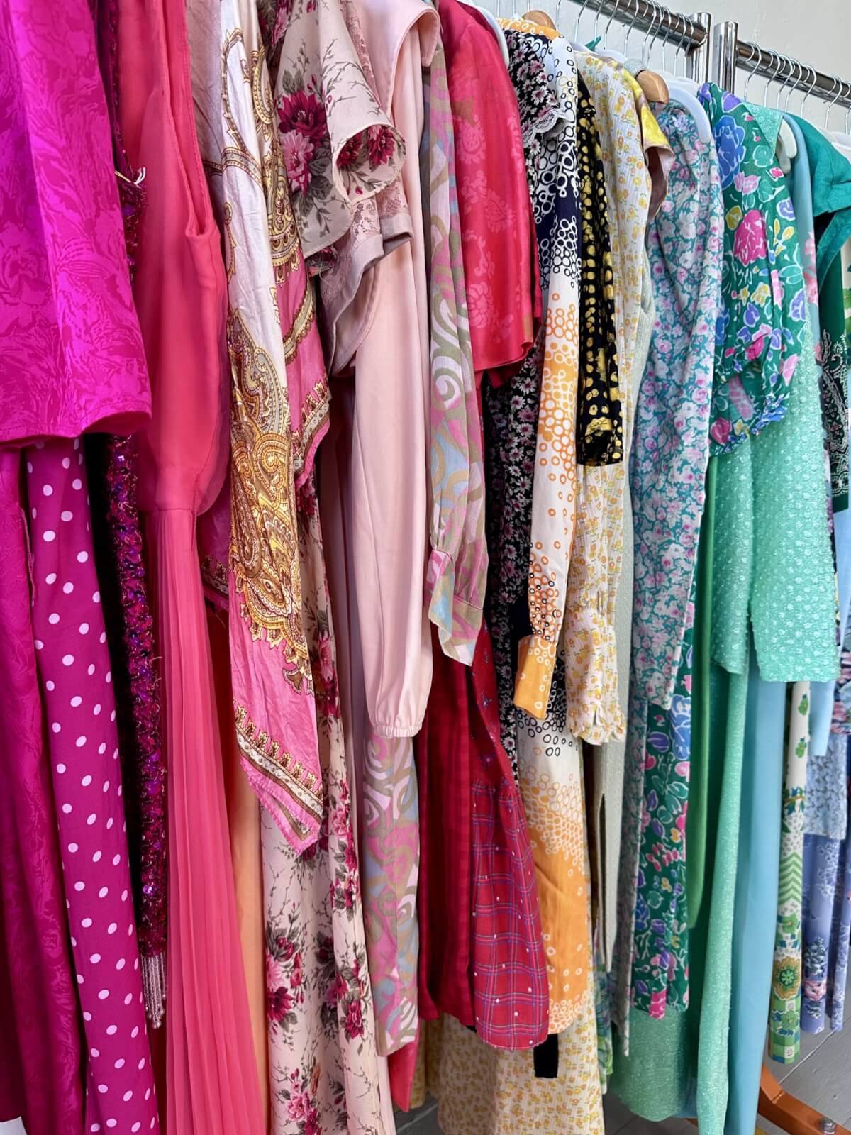 A rack of various colorful dresses with different patterns, including floral, polka dots, and solids, arranged in a row.