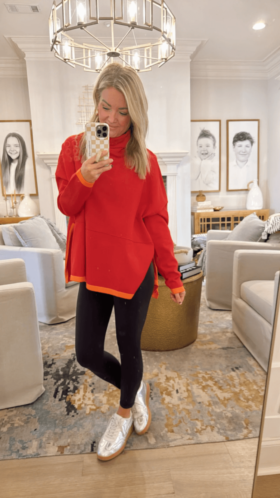 Woman in a red turtleneck sweater taking a selfie in a full-length mirror.