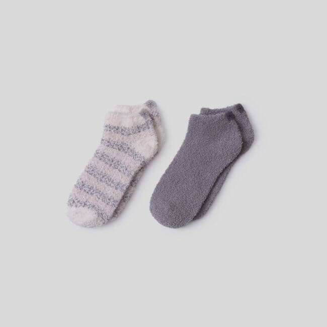 15 Memphis FINDS to See You Through January - 6 A pair of fuzzy ankle socks, one in solid gray and the other in white with gray stripes, displayed on a plain light backgroundβperfect for cozy Memphis finds this January.