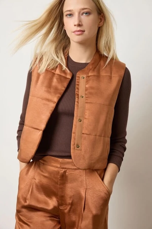 15 Memphis FINDS to See You Through January - 15 A woman wearing a brown ribbed long-sleeve top with a shiny brown vest and matching pants, standing with one hand in her pocketβa chic look inspired by Memphis finds this January.