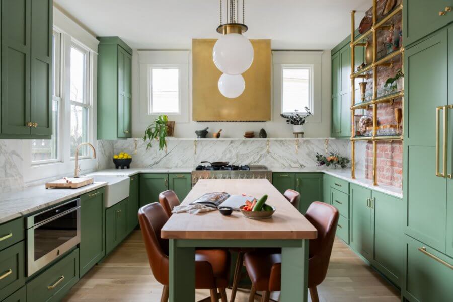 Nashville’s 10 Most Popular Articles of 2025 - 9 The green kitchen, a standout feature from Sara Ray's design, boasts marble countertops and a wooden island with leather chairs. Pendant lights illuminate the space, while white and gold accents complete the homey decor.
