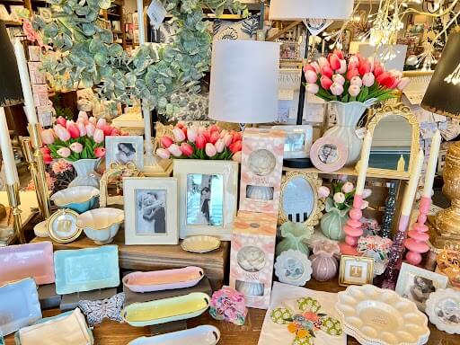 A tabletop display featuring pastel-colored ceramics, photo frames, artificial tulips, lamps, and decorative items—just a glimpse of what you’ll find at one of The Best Gift Shops in Nashville.