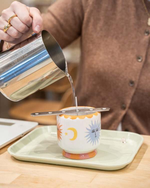 In Nashville, a person pours liquid from a metal jug into a decorative cup with celestial designs on a tray.