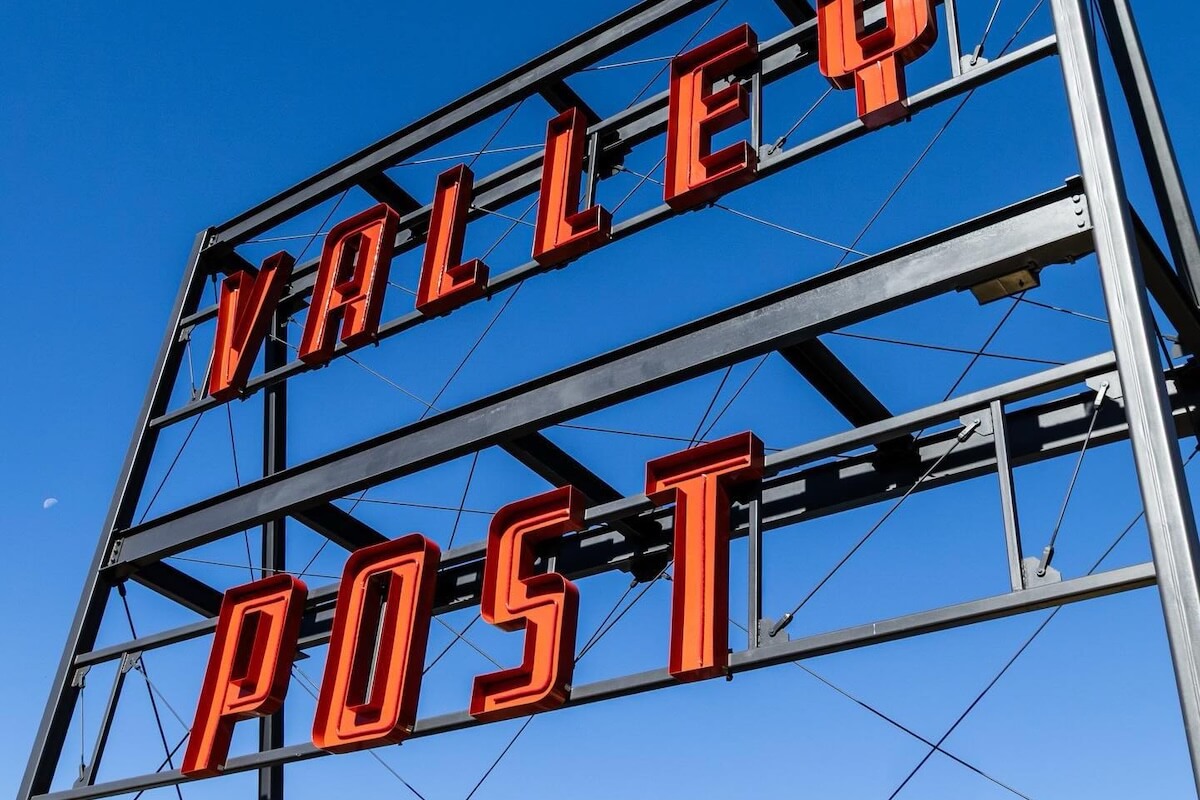 Large metal sign structure with bold red letters spelling "VALLEY POST" against a clear blue sky, welcoming those new to Birmingham.