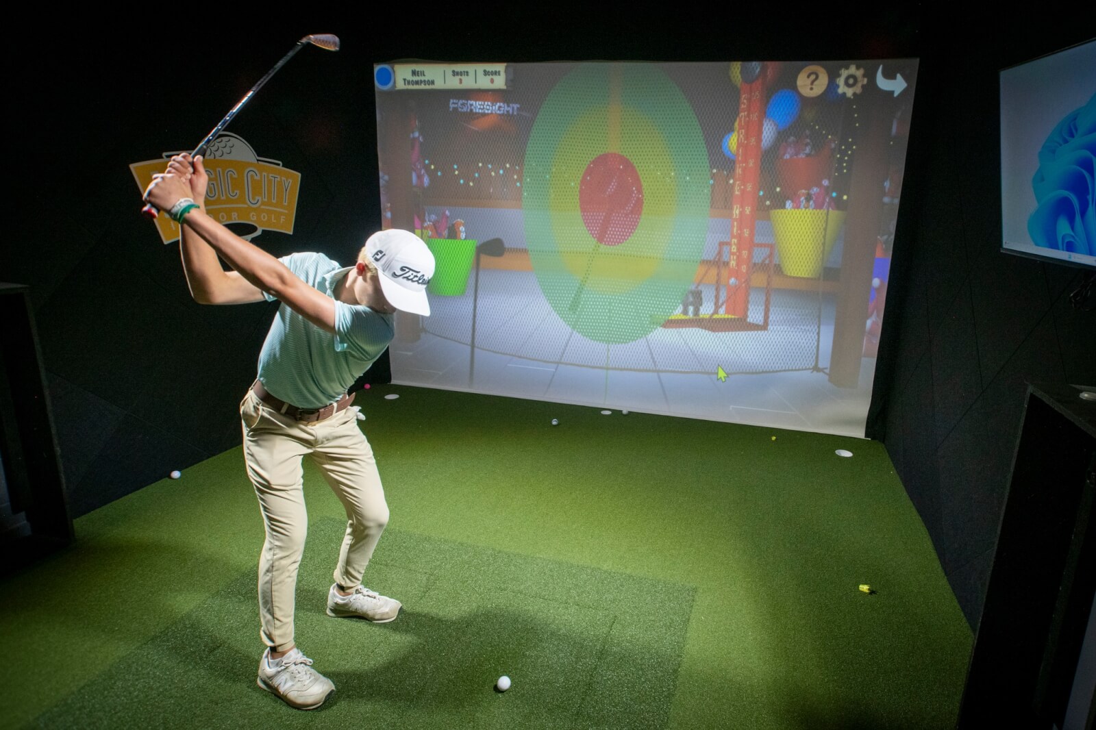 A person practices their golf swing indoors with a virtual reality simulator at Magic City Indoor Golf. 