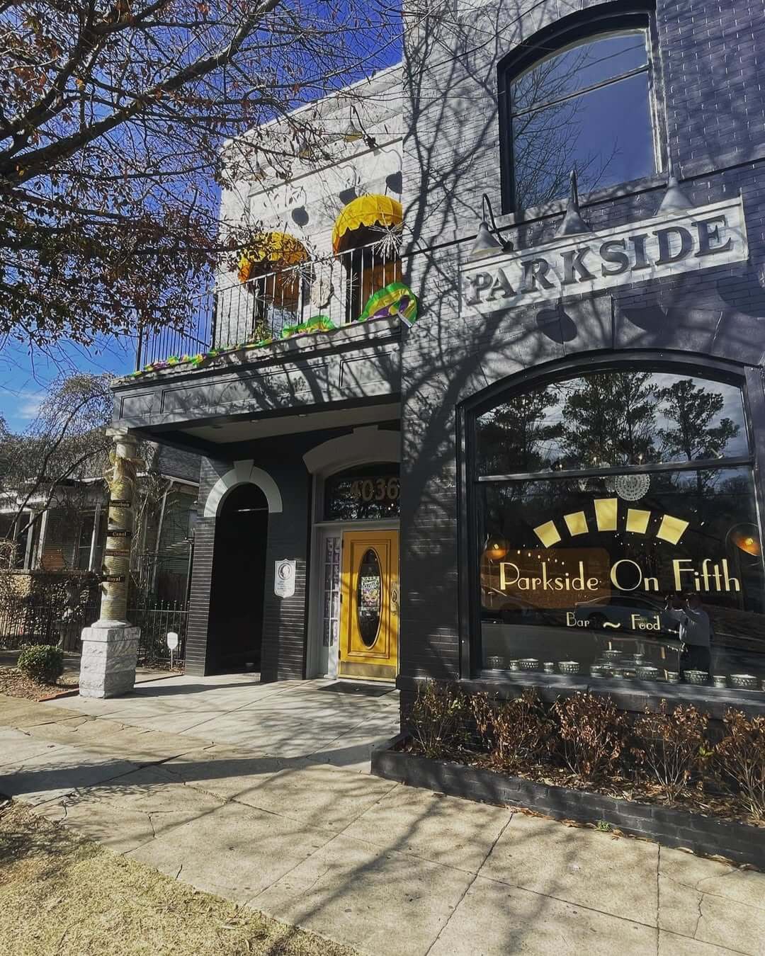 The two-story brick building, Parkside On Fifth, proudly stands in Avondale. Its yellow door and arched window exude charm, while a tree casts playful shadows on the sidewalk out front.