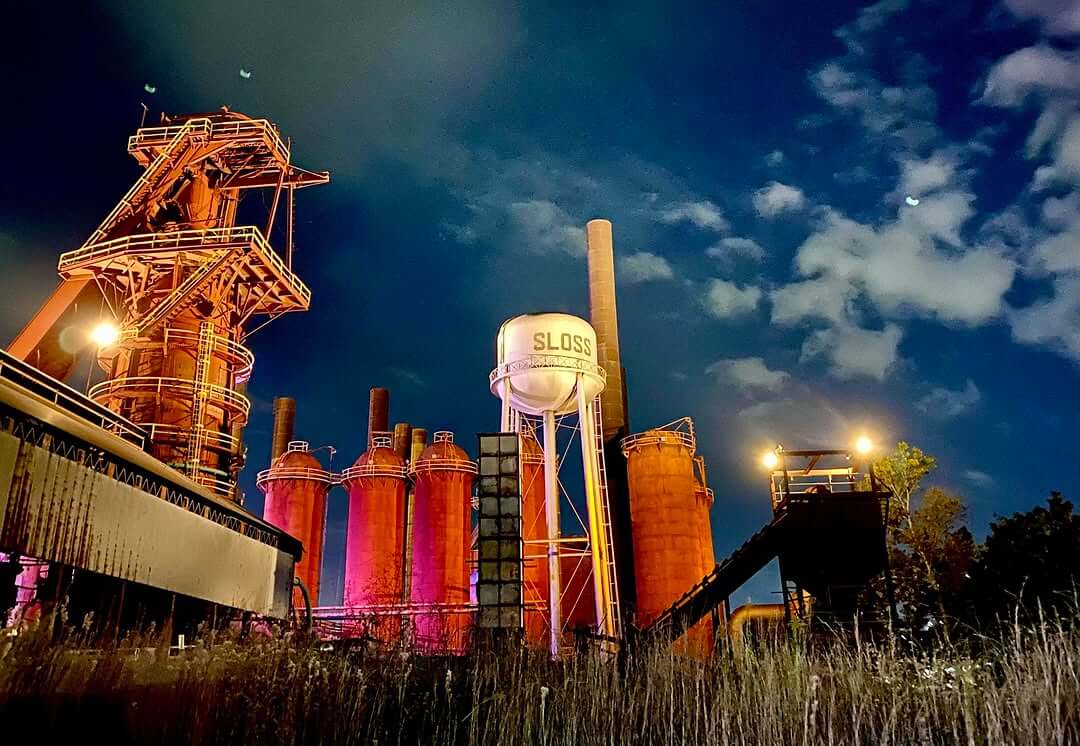 Night view of Sloss Furnaces in Avondale, with the site's industrial furnaces lit up with dramatic lighting.