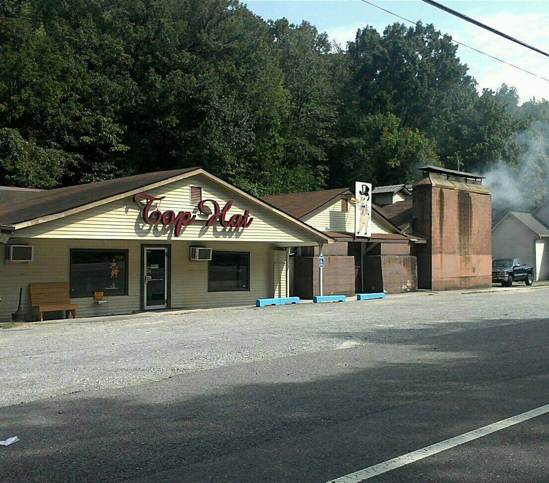 A small, single-story restaurant with a sign reading "Top Hat" sits nestled among the trees. 