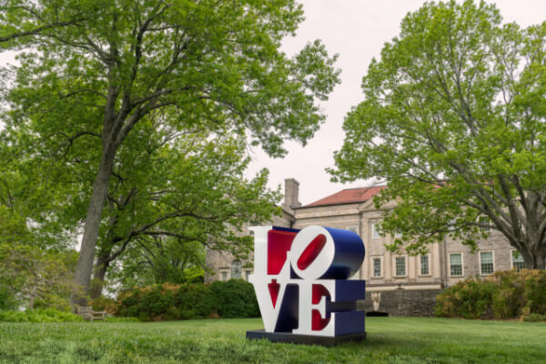 Set amid the serene greenery of Cheekwood, Robert Indiana's iconic "LOVE" sculpture in vivid red and blue stands prominently. This masterpiece, part of the Masterpiece Art Series, elegantly contrasts with the historic buildings nearby.