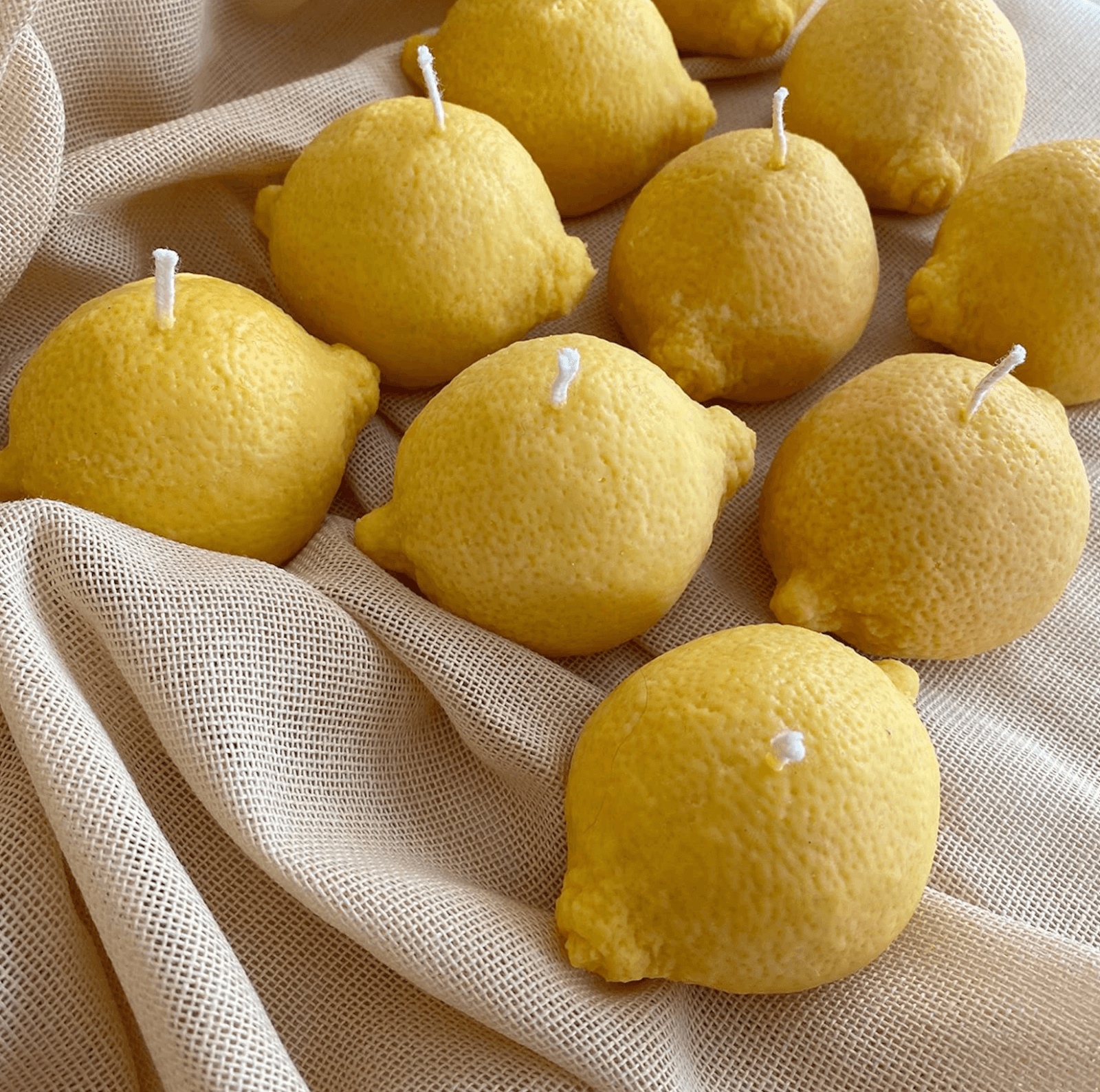 Yellow lemon-shaped candles, perfectly set against a light beige cloth background, evoking the charm of Nashville's quaint boutiques.