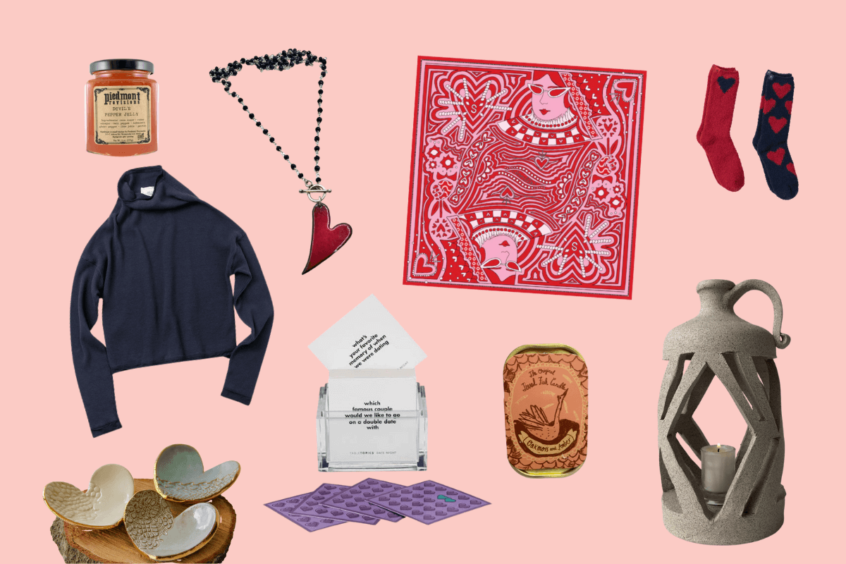 A flat lay of assorted items from Southern FINDS February, including a hoodie, necklace, bandana, socks, honey jar, coaster set, candle holder, tray, and a box with cards—all artfully arranged on a pink background.