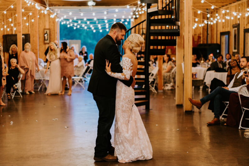 They Had the Last Pre-COVID Wedding in Vegas! - 13 A bride and groom share their first dance in a warmly litwedding reception hall. Guests are seated and standing in the background.