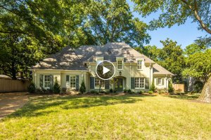 This two-story cream-colored house on Barfield Rd. features a gray roof and is beautifully nestled in Memphis, TN. It's surrounded by tall trees and a large grassy yard under a clear blue sky.