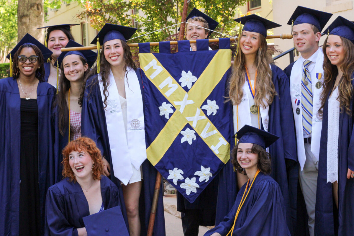 Nashville Private School Open House Dates - 11 Nine graduates in caps and gowns pose outdoors with a blue and yellow banner displaying the Roman numerals MMXXVI, celebrating their achievements at one of the regionβs esteemed private schools.