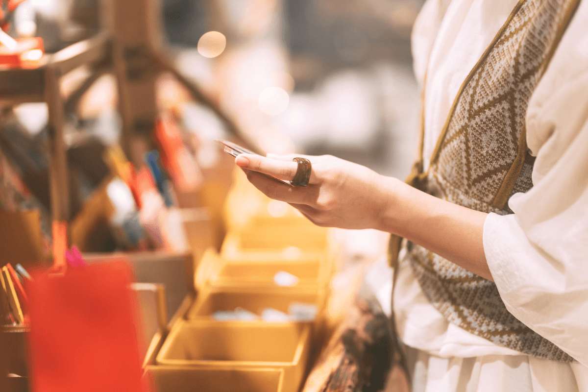 A person in a patterned vest holds a phone while standing near a display of boxed items in one of the best gift shops in Memphis.