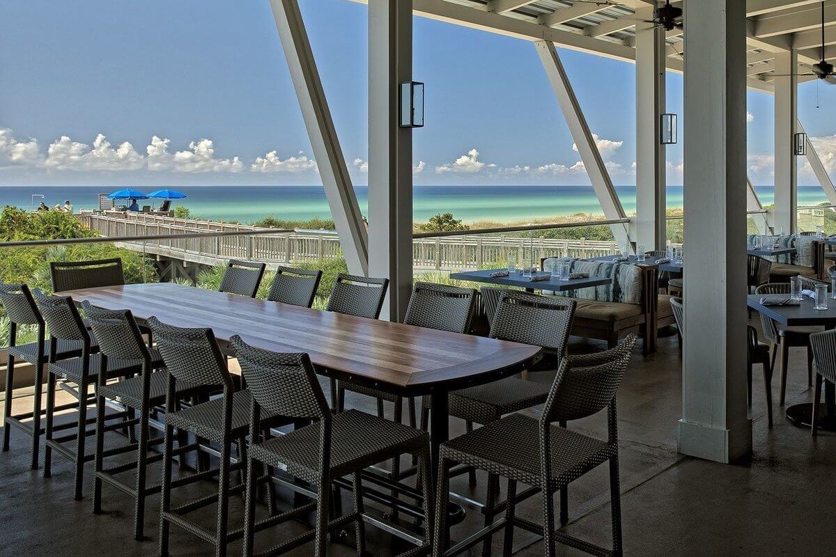 Sip cocktails at this open-air restaurant with wooden tables and chairs overlooking the beach. Enjoy clear blue skies, ocean views, and ceiling fans above as you savor the experience. 