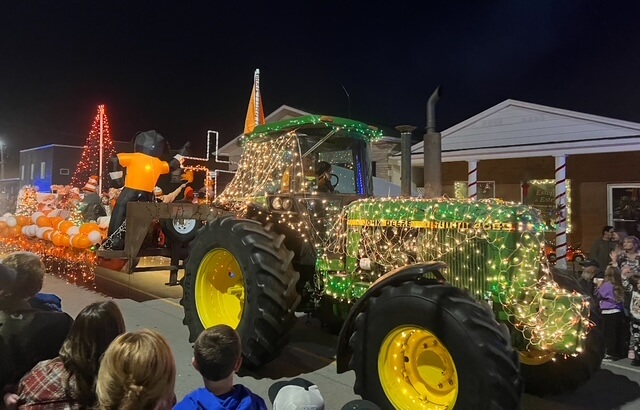 7 Best Family Vacations for Outdoor Fun - 5 A decorated tractor, covered in string lights, pulls a float with glowing pumpkins and decorations during a kid-friendly nighttime parade. It's the perfect highlight for any weekend getaway near me, capturing the amazement of families gathered to watch the spectacle.