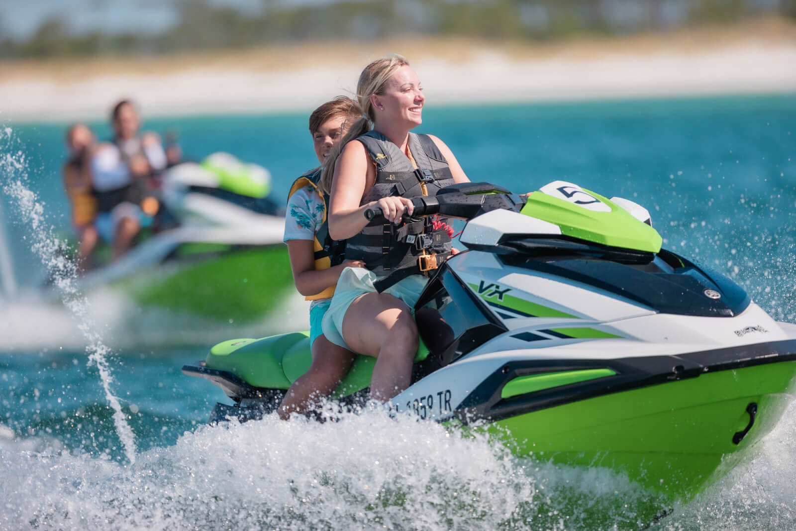 7 Best Family Vacations for Outdoor Fun - 16 Two people enjoying outdoor fun on a green and white jet ski glide across the water, with others in the background soaking up the sun on a perfect family vacation day.